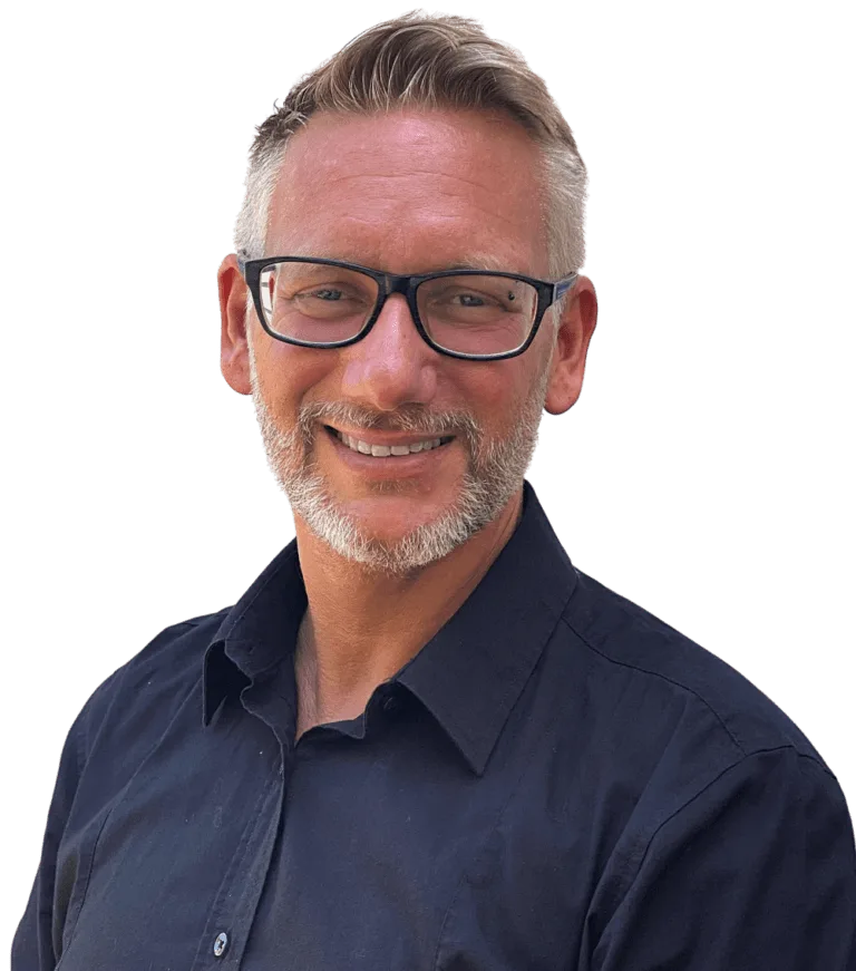 Ein Mann mit kurzen, hellbraunen Haaren, Brille und gestutztem Bart lächelt, während er ein dunkles Button-up-Hemd trägt und bereit ist, Ihnen beim WordPress reparieren zu helfen. Er steht vor einem schlichten weißen Hintergrund.